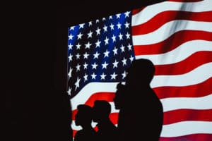 silhouettes in front of the American flag - Dan Moisand discusses if the 2020 presidential election will make the market crash